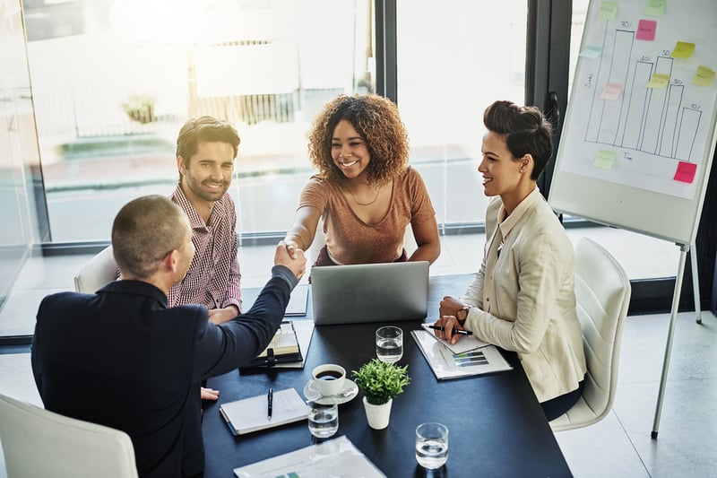 HR professionals smiling and shaking hands with a candidate who completed a talent assessment